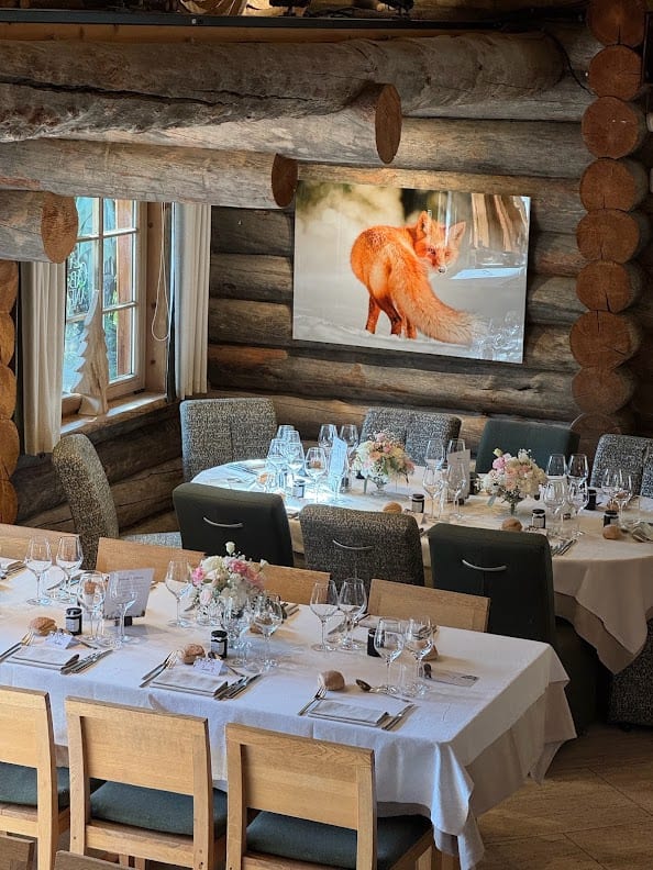 La salle en rondins de La Cabane des Praz, tables dressées et tableau de renard au mur