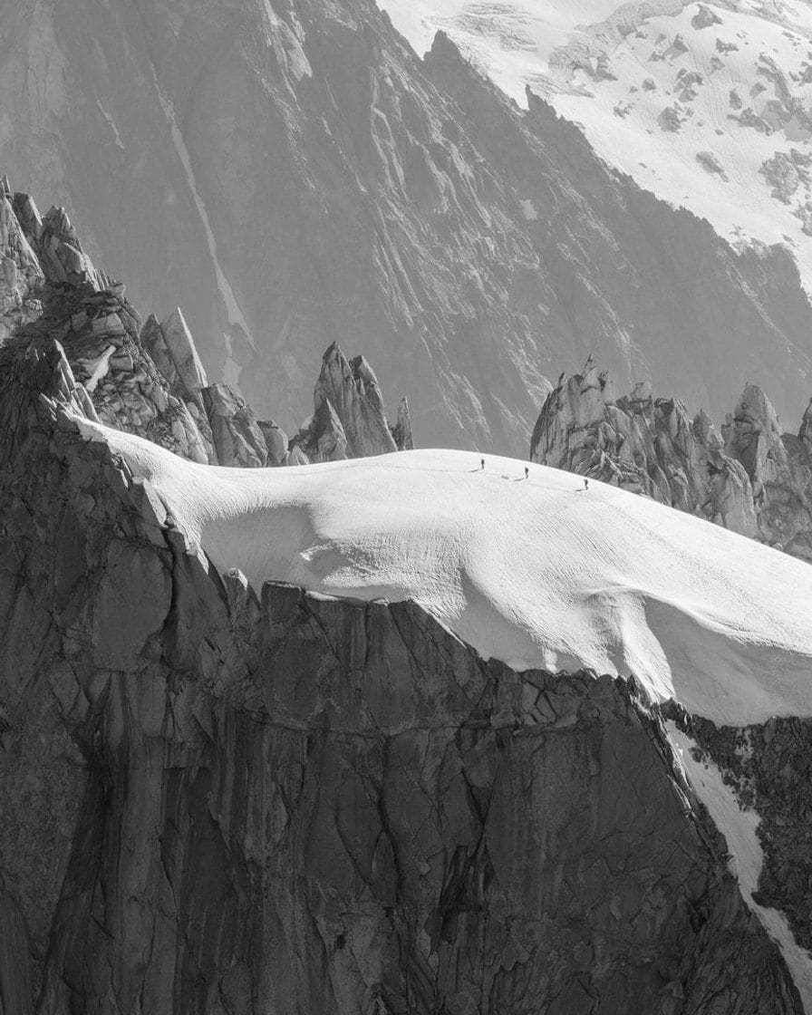Tiny climbers on the snowy ridge of the Aiguille du Midi, in black and white
