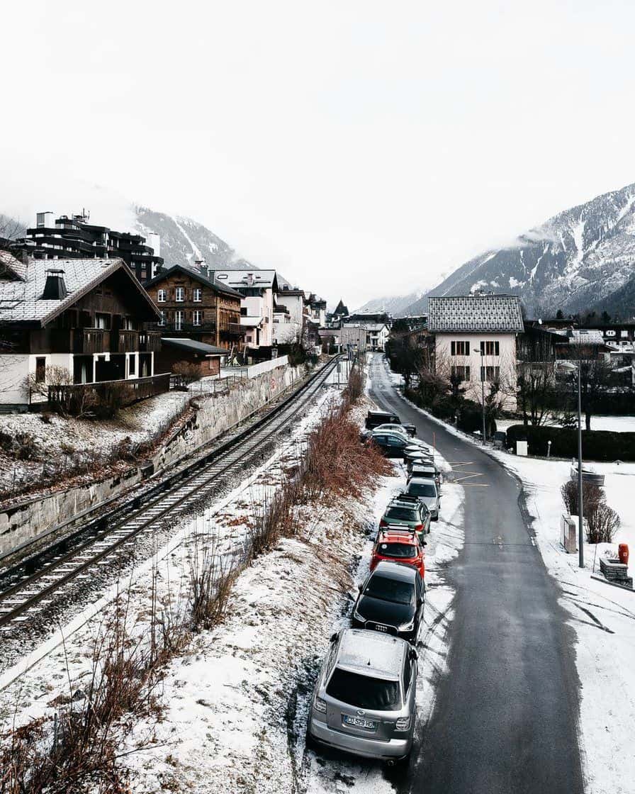 Village in the Chamonix valley under snow, railway line and cars parked along the road