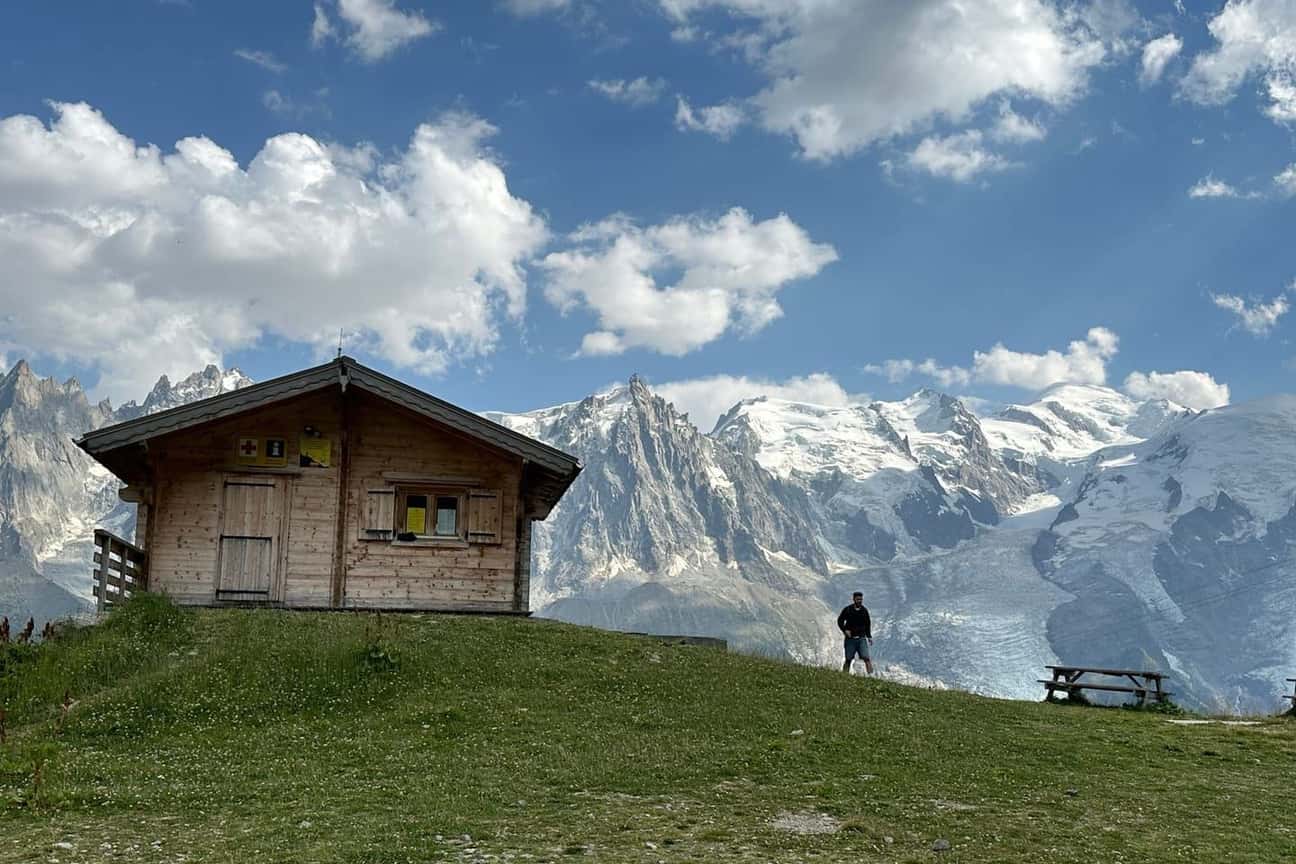 A small wooden chalet on a grassy slope above Chamonix, facing the glaciers of the Mont Blanc massif, photographed in summer