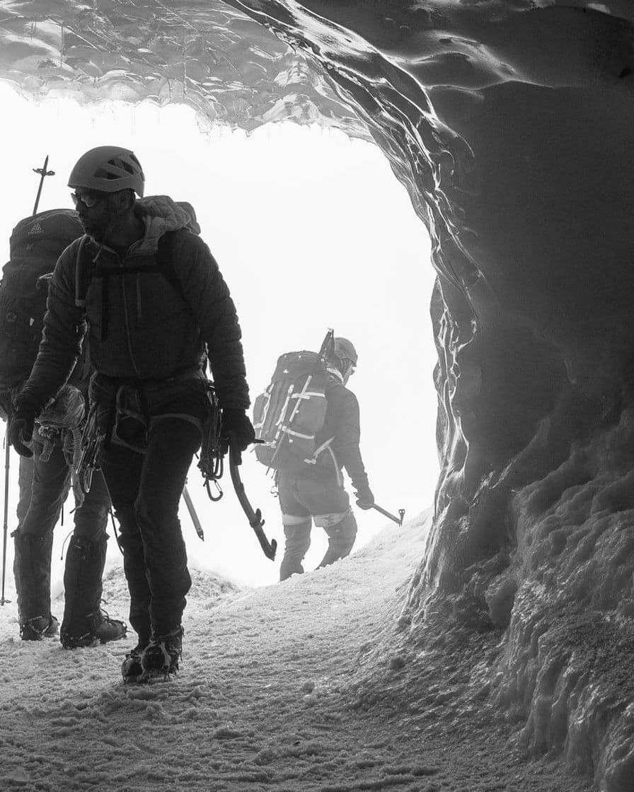 Alpinistes qui sortent d'une galerie de glace, en noir et blanc