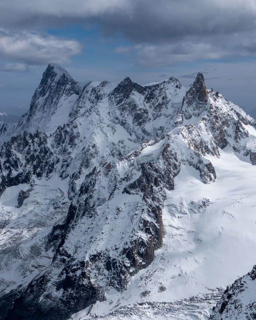 Rocky, snowy face of the Mont Blanc massif under a cloudy sky