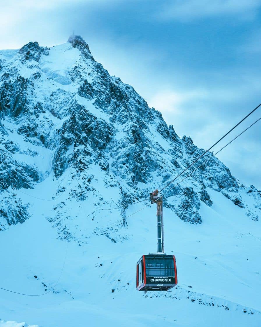 Cabine de téléphérique au-dessus des pentes enneigées, sous les aiguilles de granit du massif