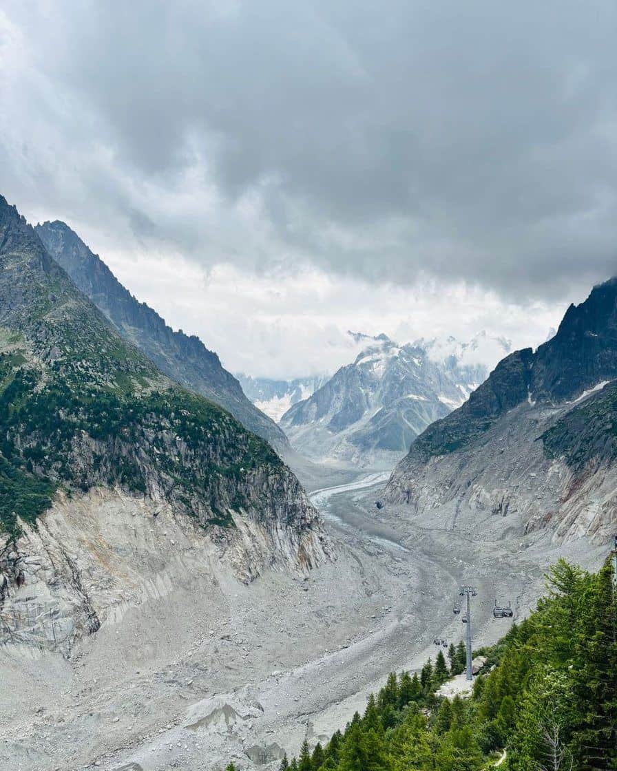 The Mer de Glace between its rocky slopes, seen from above under a cloudy sky